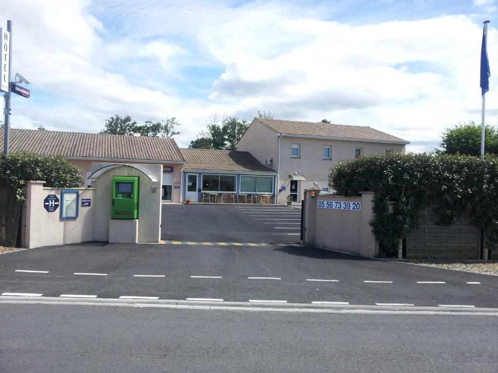 - un parking avec un bâtiment doté d'une porte verte dans l'établissement Tour Hôtel, à Lesparre-Médoc