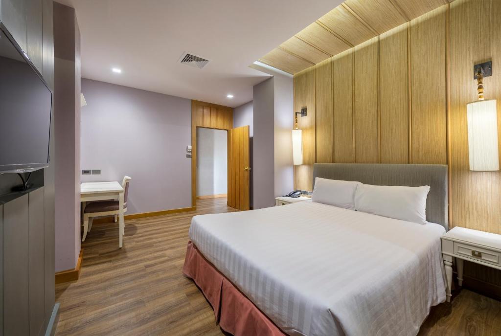 A bright bedroom with a double bed, television and compact desk.