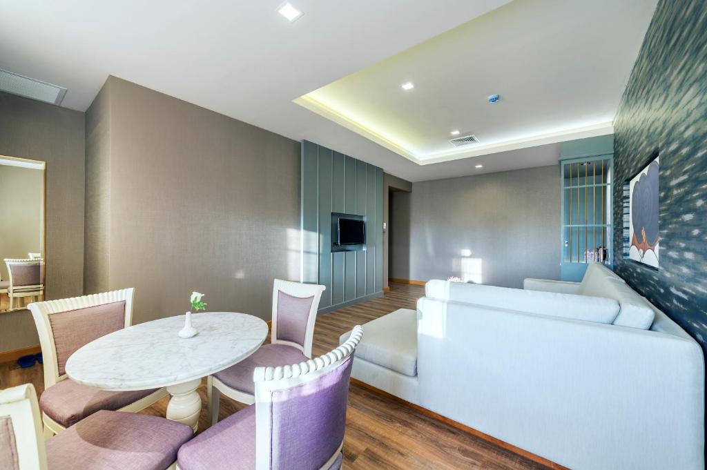A spacious sitting and dining room with a sectional sofa and round table.
