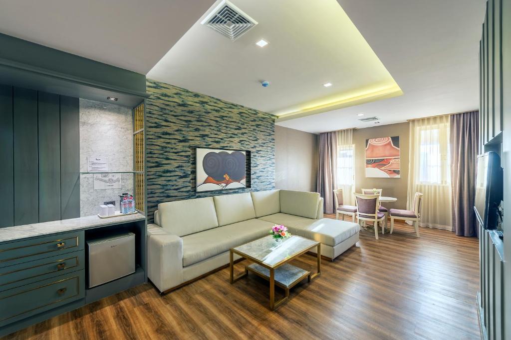 A spacious suite-style sitting room with a sofa, kitchenette cabinet and window seating.