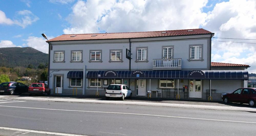 a white car parked in front of a building at Pension Grilo in Padrón