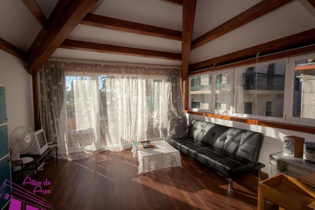 a living room with a black leather couch and a window at Ático del Arco in Cangas de Morrazo