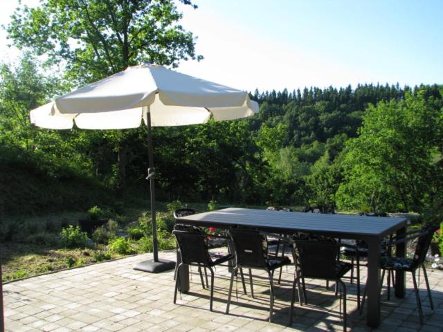 einen Tisch und Stühle unter einem Sonnenschirm auf einer Terrasse in der Unterkunft Holiday Home Pandora in Bouillon