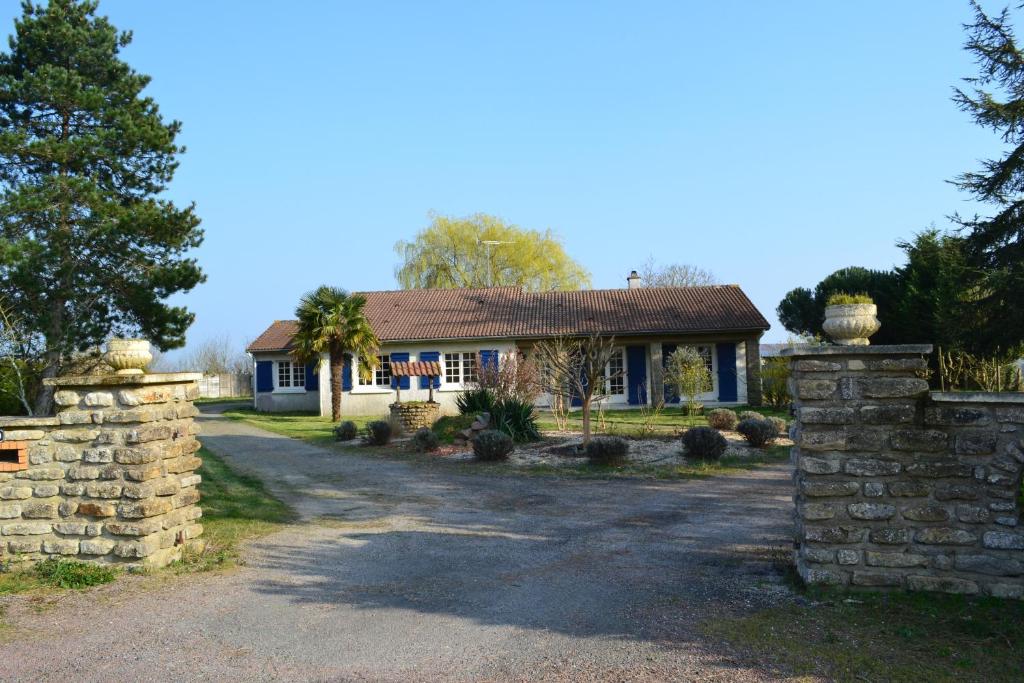 a house with a stone fence in front of a driveway at Chambre d'hôtes la ville en bois in Mouchamps