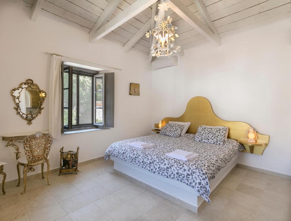 a bedroom with a bed and a chair and a chandelier at Villa Sunrise in Hydra