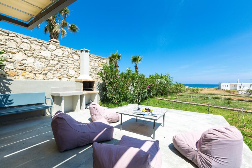 un patio con mesa, sillas y el océano en Yiannis Apartments, en Adelianos Kampos