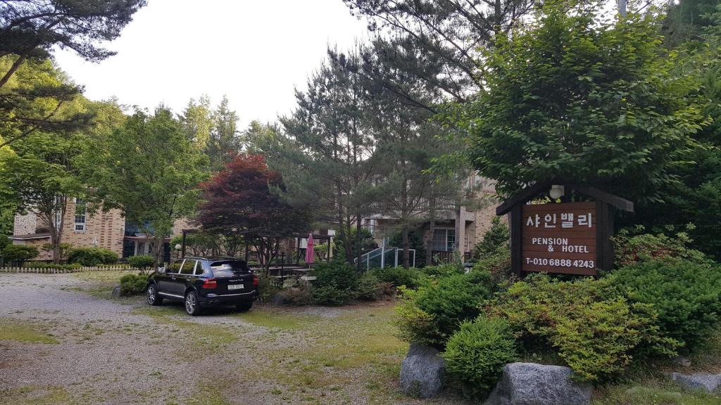 a parking lot with a sign in front of a house at Shinevalley Pension & Hotel in Pyeongchang