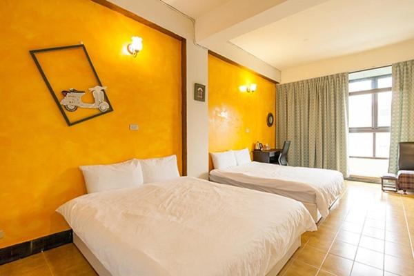 two beds in a hotel room with yellow walls at Sailin 137 Hostel in Tainan