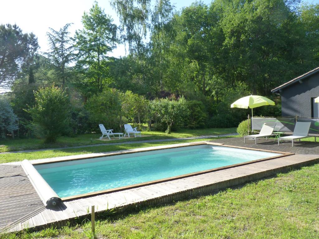 una piscina en un patio con sillas y sombrilla en A l'Heure d'Eté, en Fargues-de-Langon