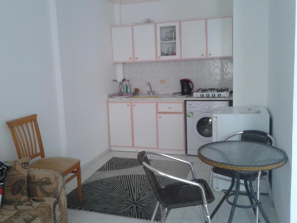 マフムトラールにあるAygun Apartment 2の白いキャビネット、テーブルと椅子付きのキッチンが備わります。