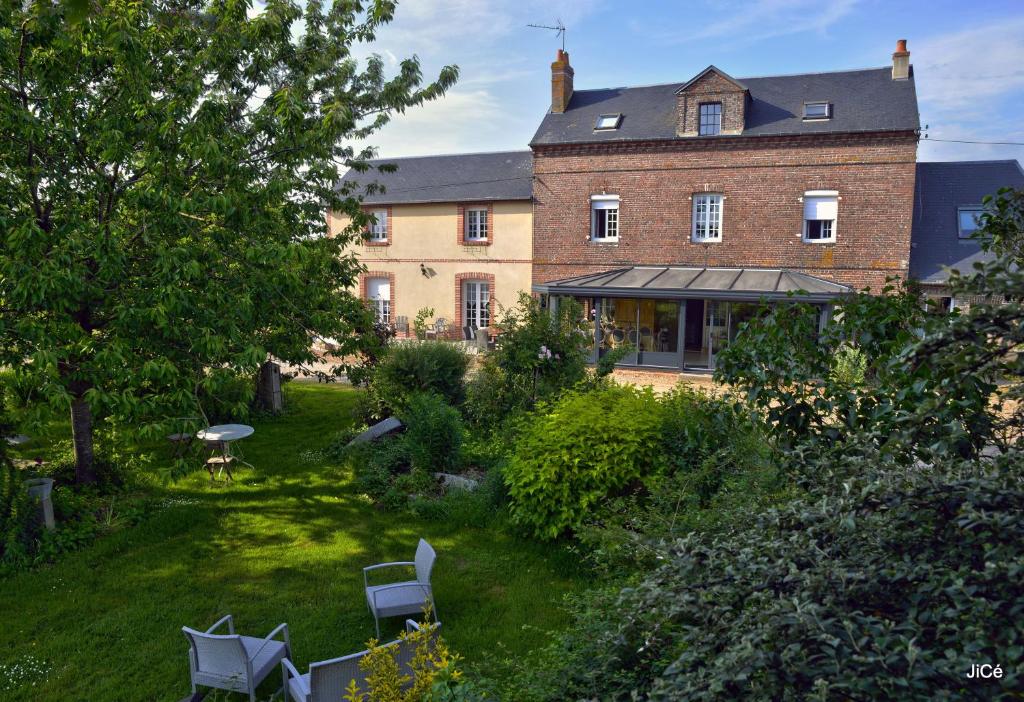een groot bakstenen gebouw met een tuin met stoelen bij Chambres d'hôtes Ferme du Feugrès in Saint Germain la campagne