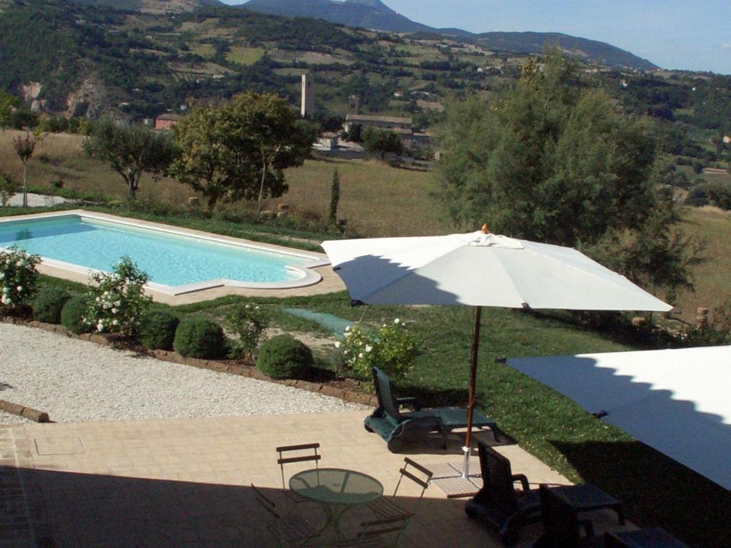 an umbrella and chairs next to a swimming pool at Al Castello in San Severino Marche