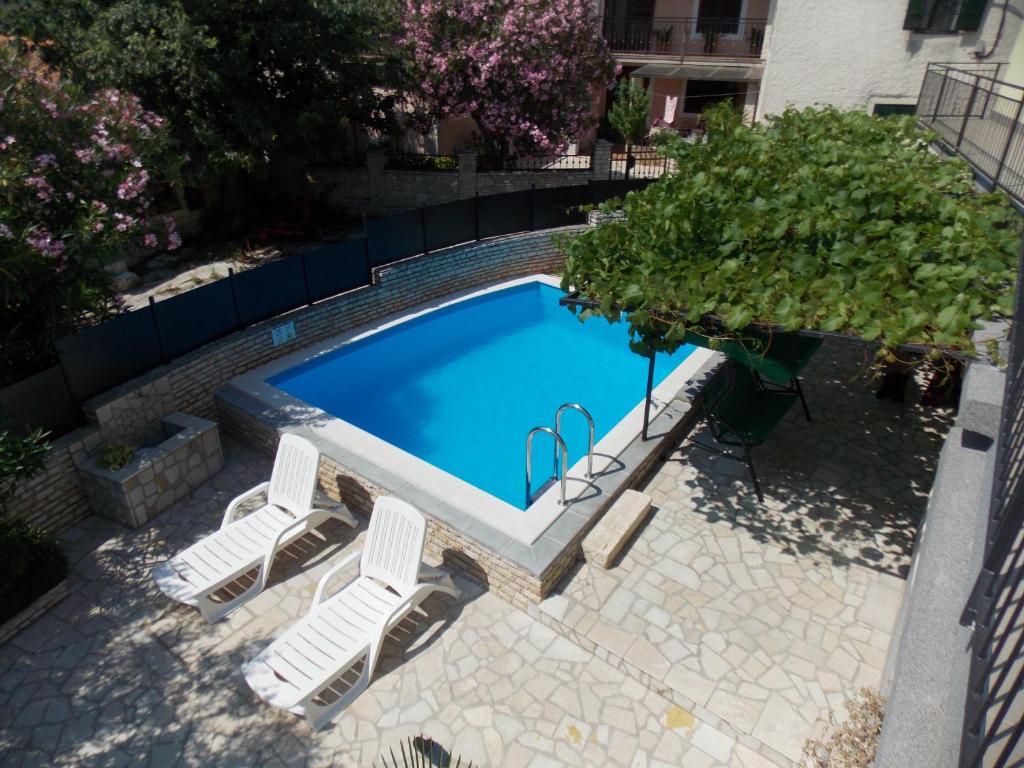 einen Blick über einen Pool mit zwei Stühlen und einem Baum in der Unterkunft Aurelia Apartment in Ližnjan