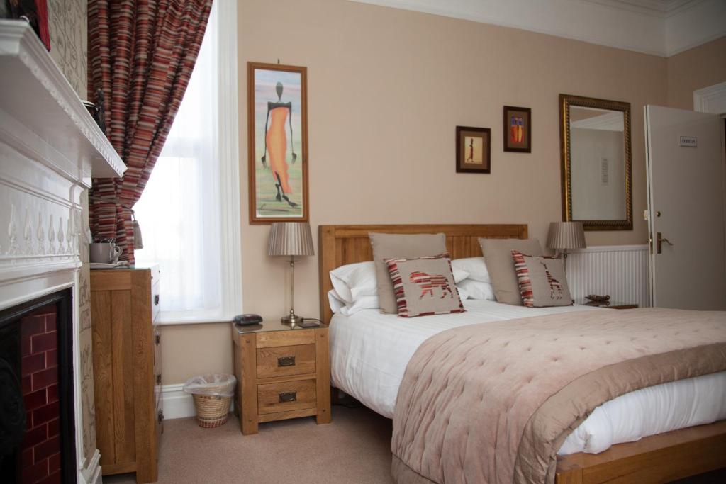 a bedroom with a large bed and a fireplace at The Langtons Bed & Breakfast in Eastbourne