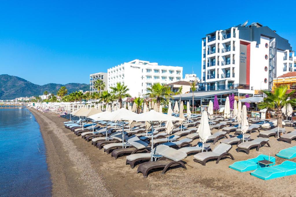 un montón de sillas y sombrillas en una playa en Marmaris Beach Hotel, en Marmaris