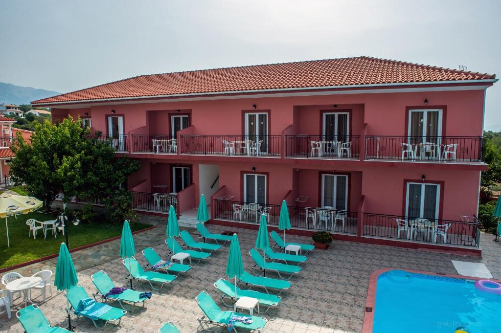 a large red building with chairs and a swimming pool at Paradise Studios in Svoronata