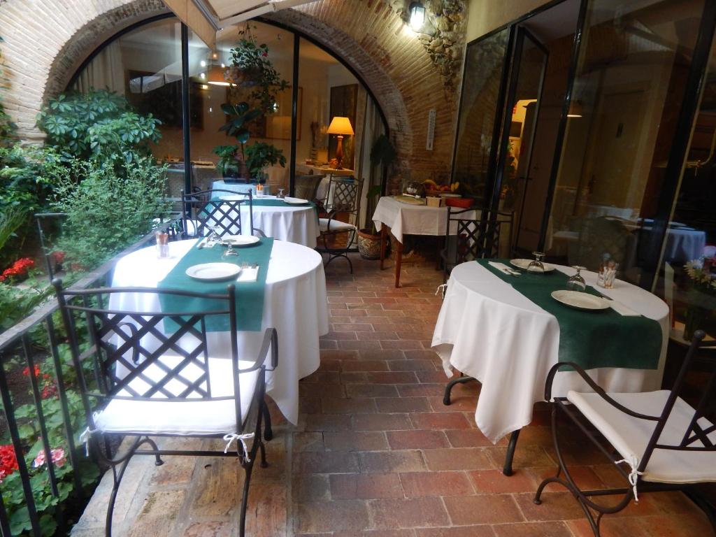 un restaurant avec deux tables recouvertes de nappes vertes et blanches dans l'établissement Hotel de La Font Peralada, à Peralada