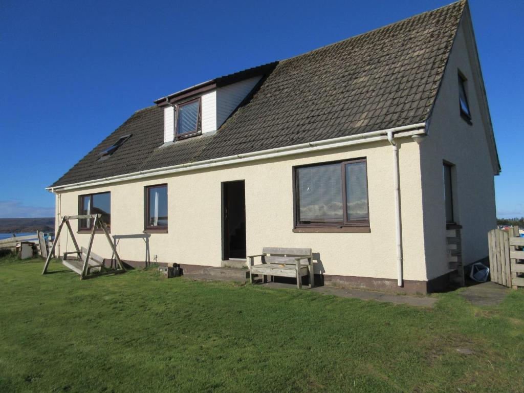 una casa con una mesa y un banco delante de ella en Taighali Apartment, en Aultbea