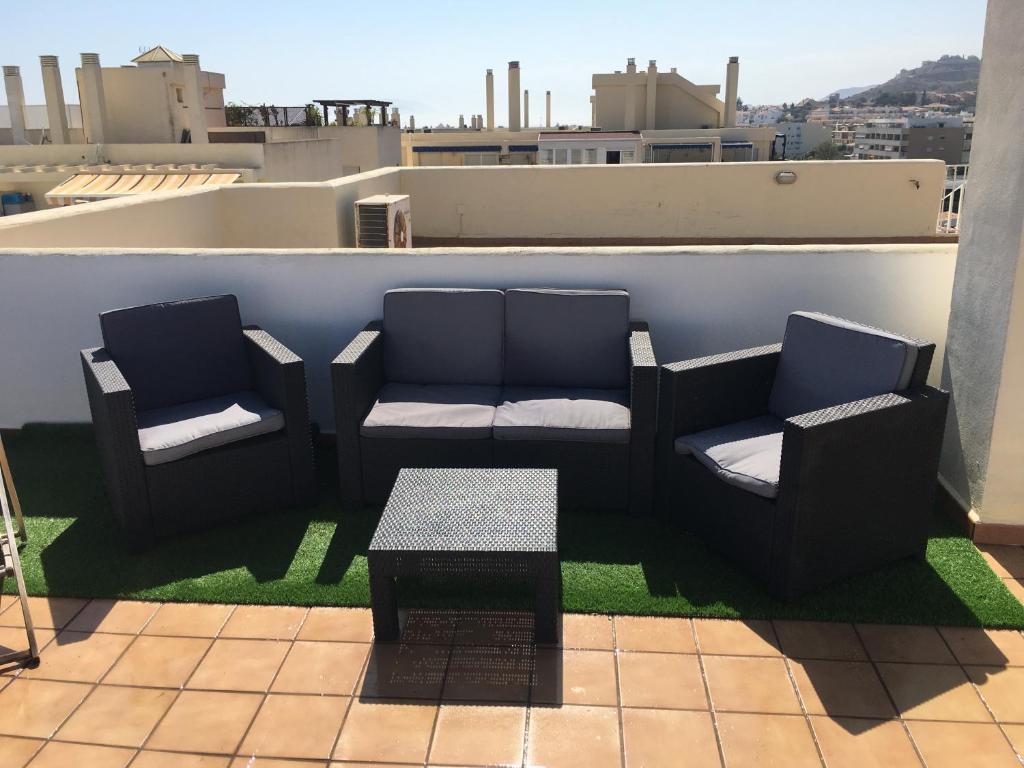 un patio avec deux chaises et une table sur le toit dans l'établissement Apartamento Ático a 50 metros de la playa Will, à Rincón de la Victoria