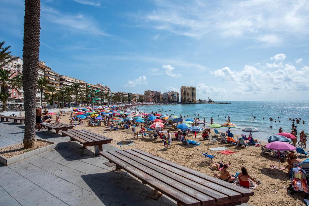 un gruppo di persone su una spiaggia con ombrelloni di Apartments Slice of Life a Torrevieja