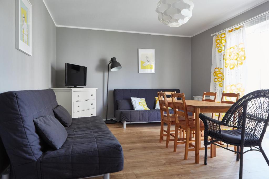 ein Wohnzimmer mit einem Sofa und einem Esstisch in der Unterkunft Sunrise Apartamenty in Łeba
