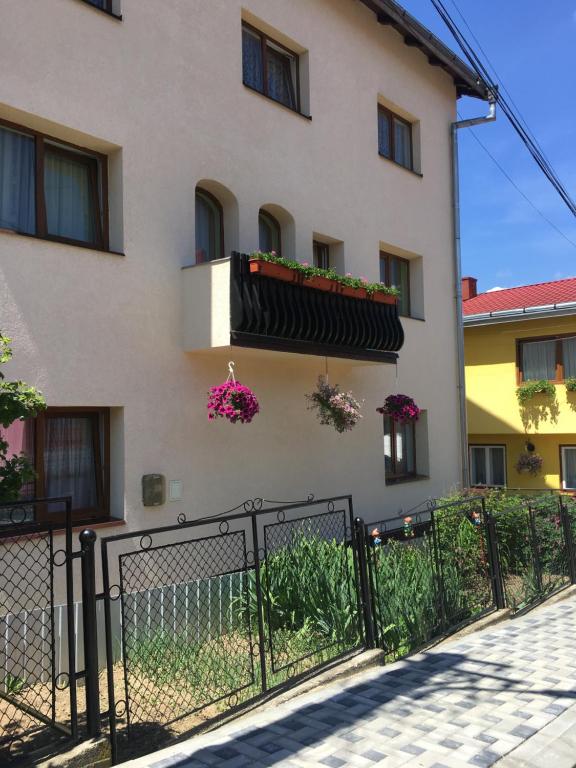 a building with a fence and flowers on a balcony at Pensiunea Alecsandra in Vatra Dornei