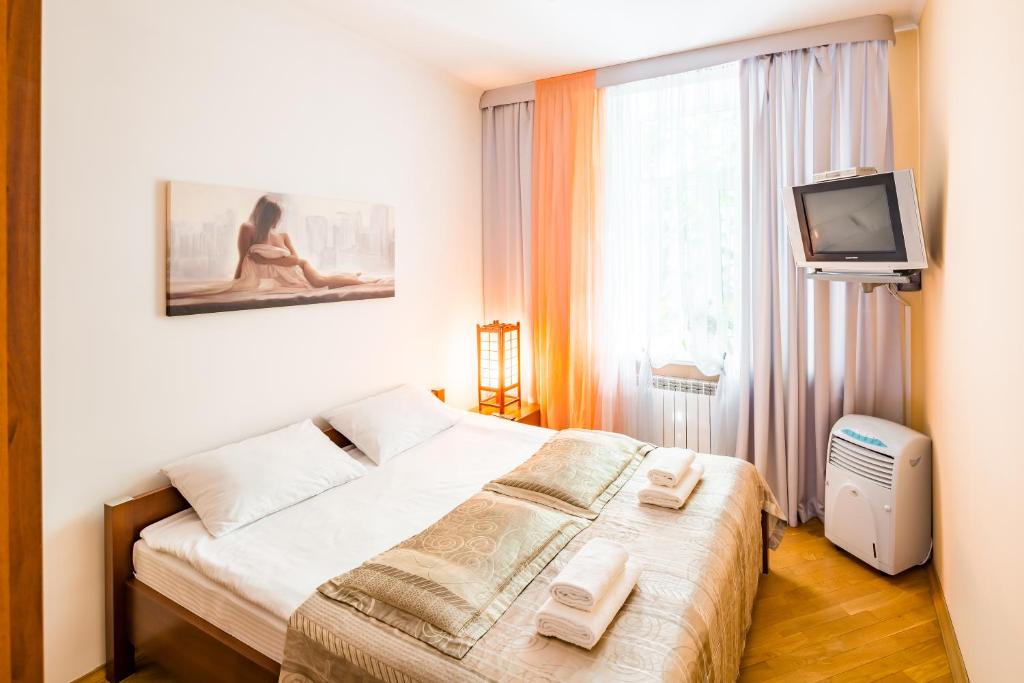 a bedroom with a bed and a tv and a window at Apartment on Arkhipenka with Panorama View in Lviv