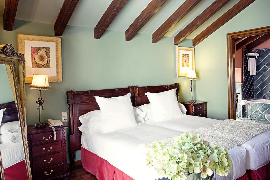 a bedroom with a bed with white sheets and flowers at Hotel Montelirio in Ronda