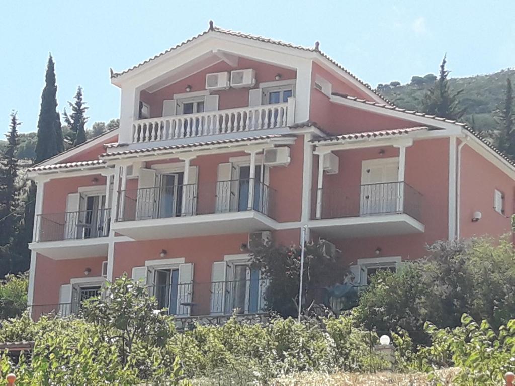 una gran casa rosa en una colina con árboles en Myrtos Hotel, en Divarata