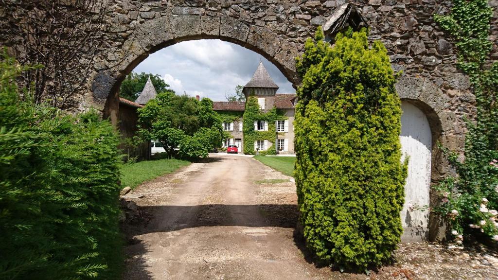 an archway in a stone wall with a house at Pierre Deluen Domaine de la Grange de Quaire in Chassenon