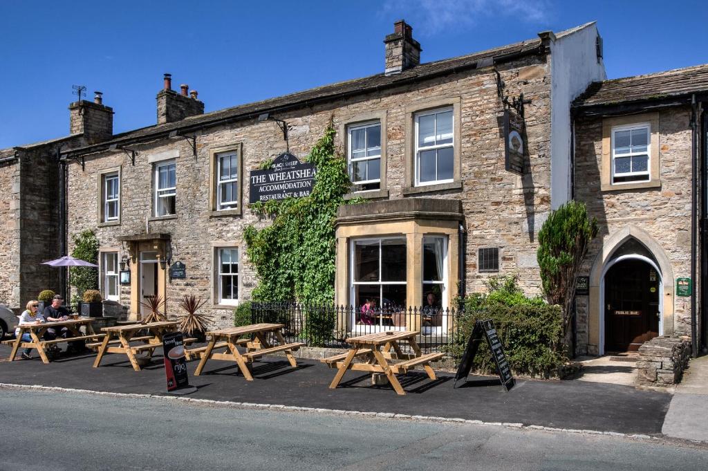 um edifício com mesas de piquenique em frente em The Wheatsheaf Inn em Carperby