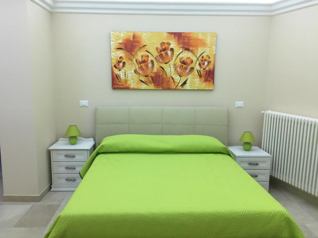 パラービタにあるB&B Il Ventaglioの緑のベッドと壁に絵画が飾られたベッドルーム1室