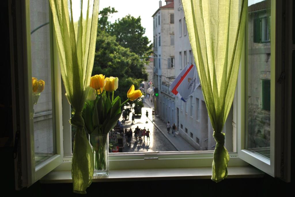 a window with yellow flowers in a vase on a window sill at Optimist split/city center in Split