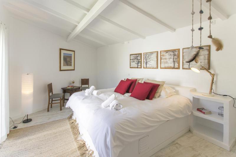 a white bedroom with a large white bed with red pillows at O Moinho da Roca in Azoia