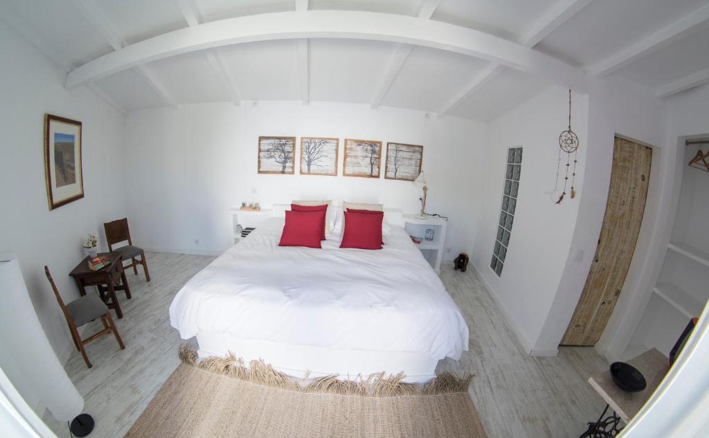 a bedroom with a large white bed with red pillows at O Moinho da Roca in Azoia