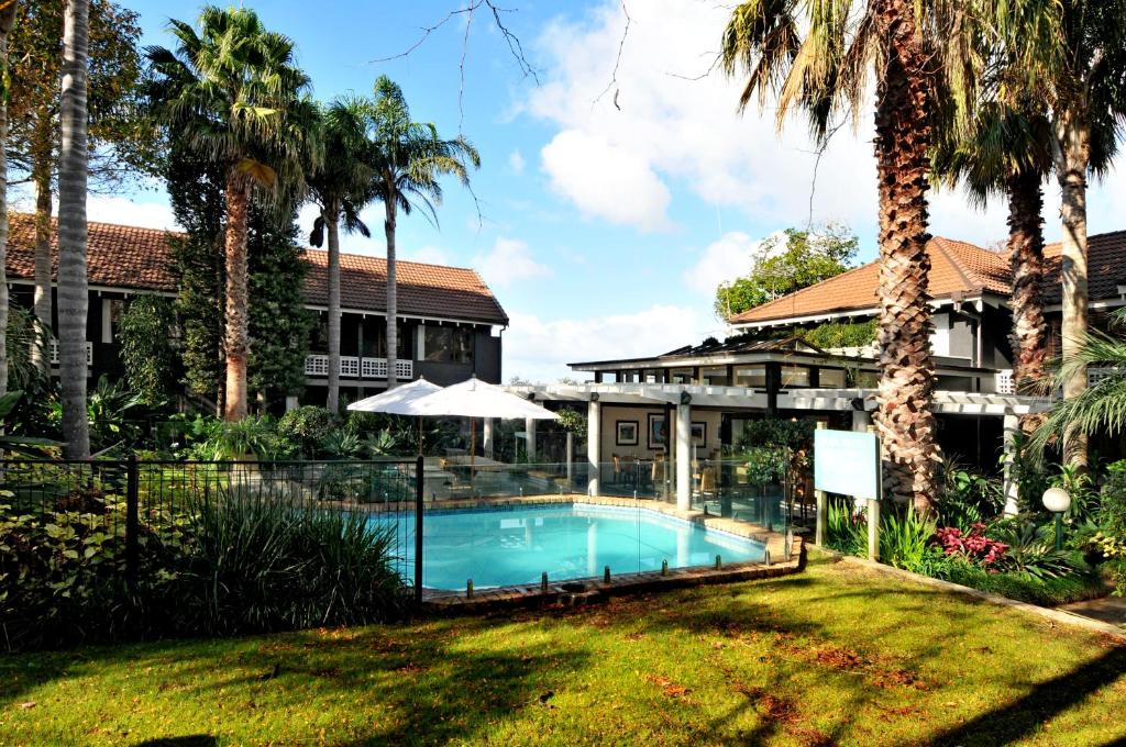 a swimming pool in front of a house with palm trees at Emerald Inn on Takapuna Beach in Auckland
