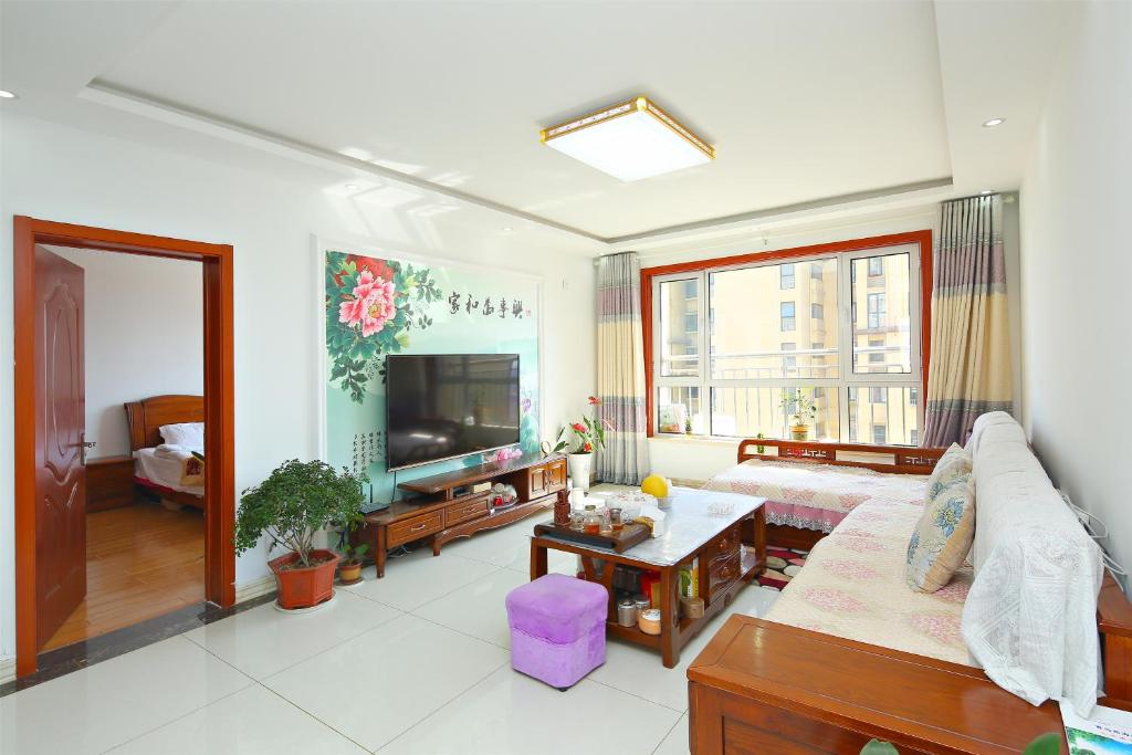 a living room with a couch and a tv at 青岛金沙滩全家幸福三居室海景公寓Blessed Family Apartment in Qingdao