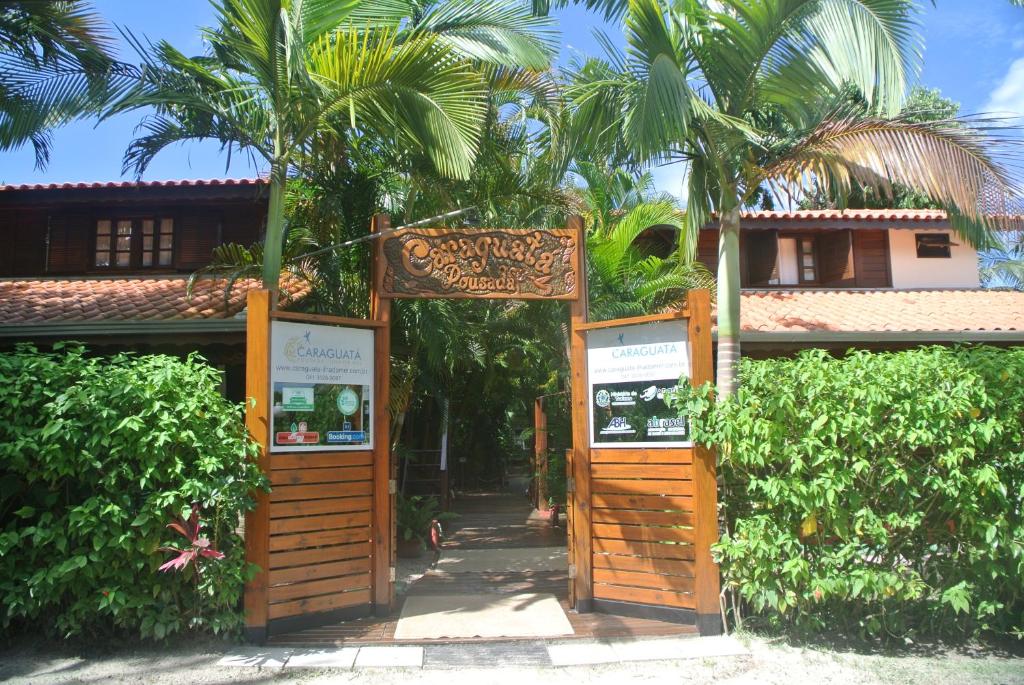 a sign in front of a building with trees at Complexo de Pousadas Caraguatá in Ilha do Mel