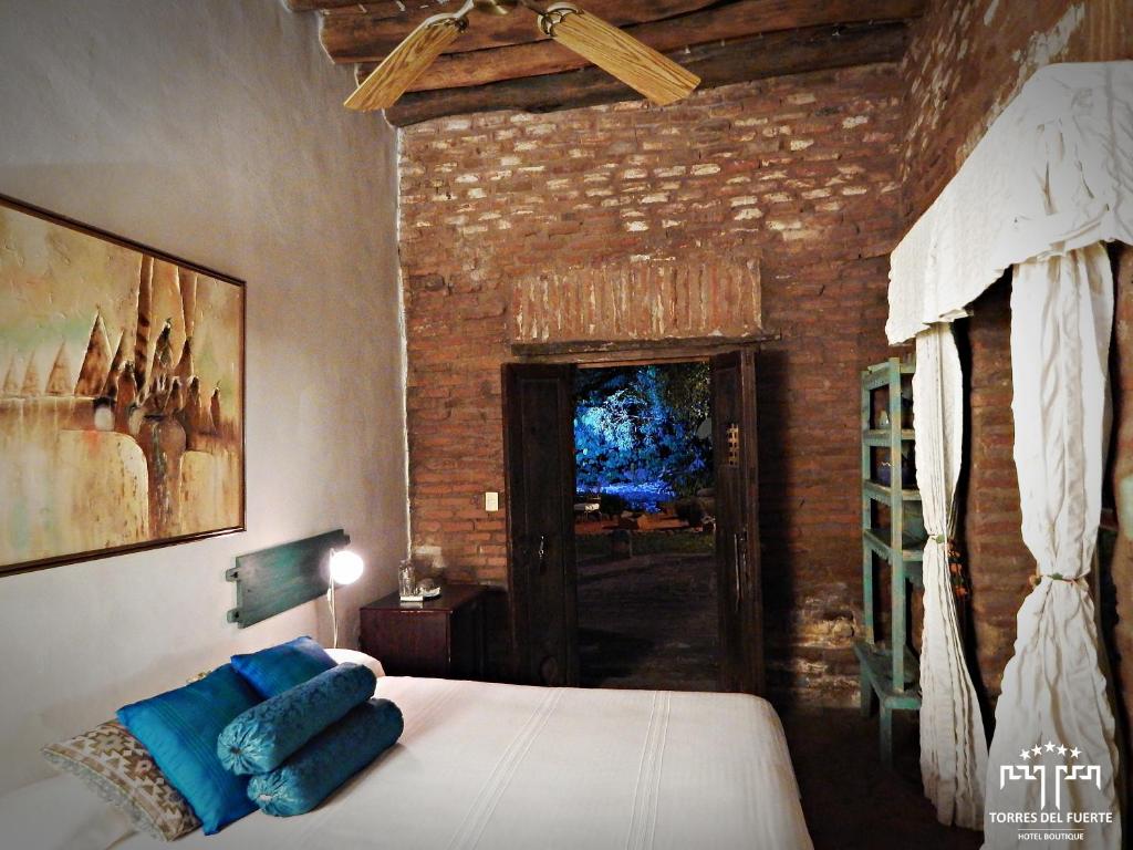 a bedroom with a bed with blue pillows on it at Hotel Torres Del Fuerte in El Fuerte