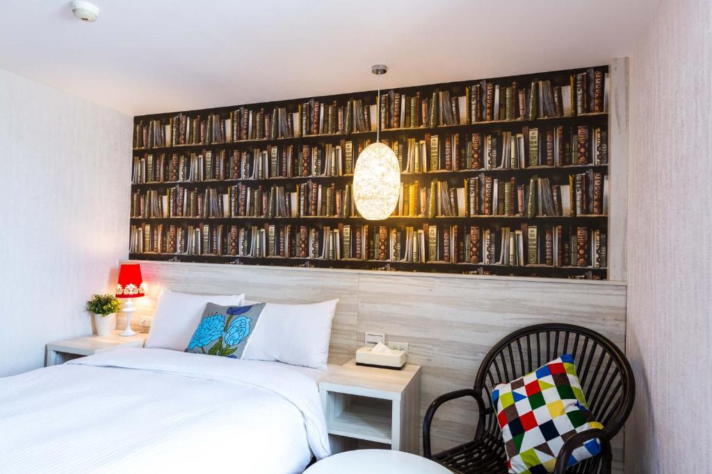 a bedroom with a bed and a wall of books at Artch Inn in Luodong