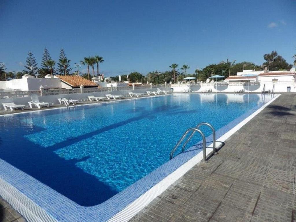 a large swimming pool with chairs and blue water at Casita Dayana - Costa del Silencio in Costa Del Silencio