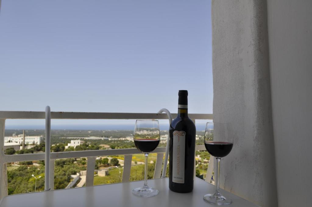 a bottle of wine and two glasses on a balcony at Latorreangioina in Ostuni