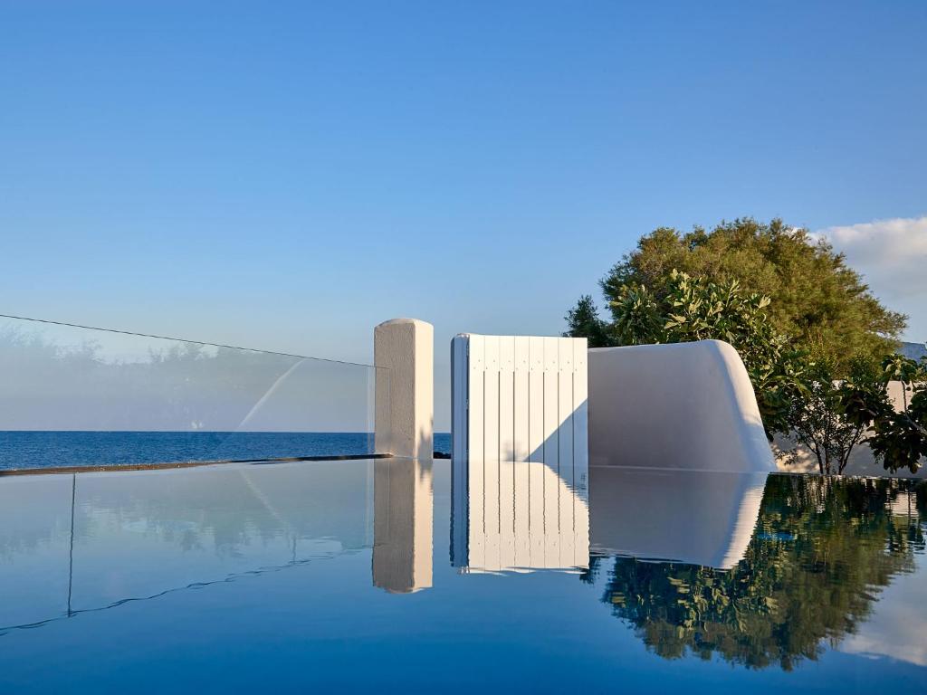 uma piscina com uma cadeira branca e água em Incognito Beach Villa Santorini em Kamari