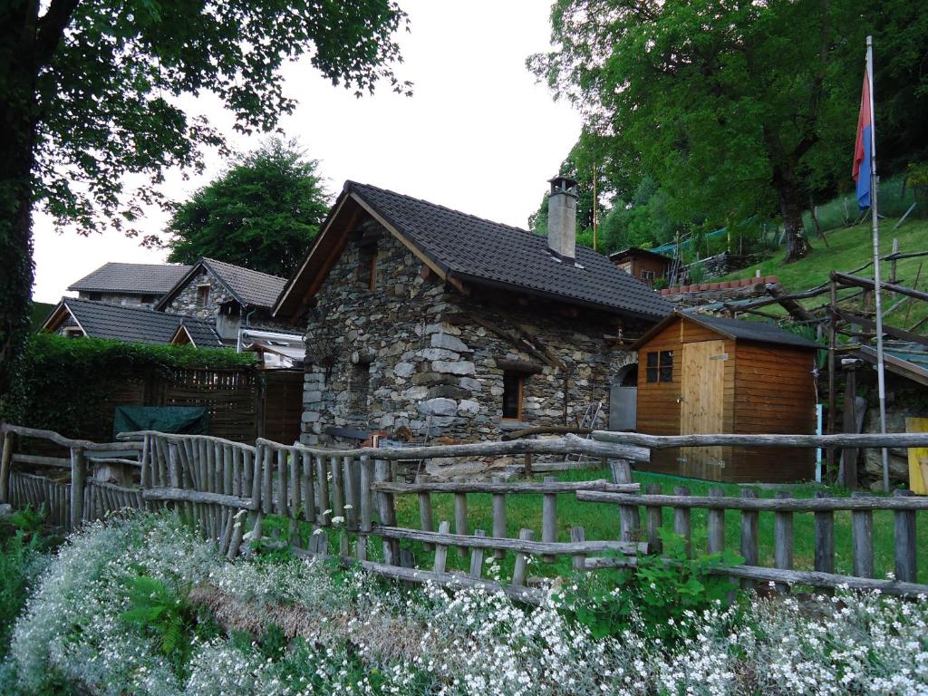 uma casa de pedra com uma cerca de madeira em frente em Casa Poiana em Ronco sopra Ascona