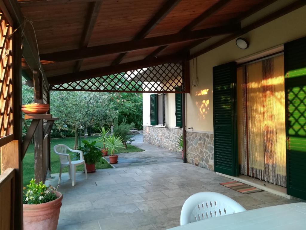 patio z białymi krzesłami i drewnianą pergolą w obiekcie Il Giardino degli Ulivi w mieście Rapolano Terme