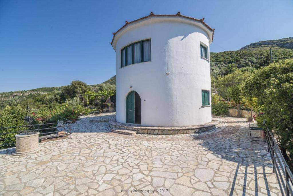 a white building with a green door on a stone patio at Razos Windmill in Vathi
