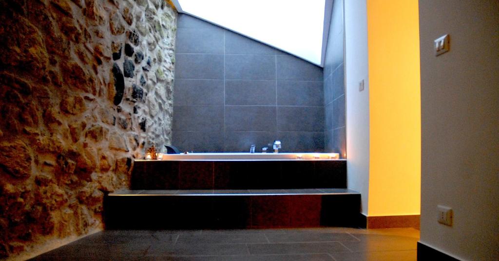 ein Badezimmer mit einer Badewanne und einer Ziegelwand in der Unterkunft Yuba - Aragon home holiday in Montalbano Elicona