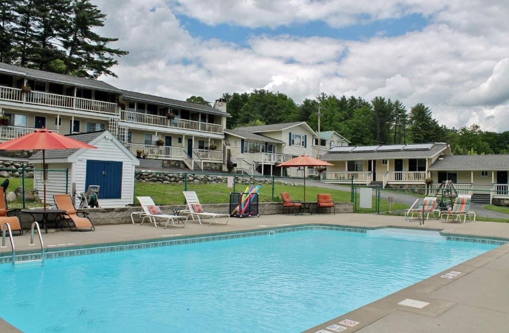 una piscina con sillas y sombrillas frente a un hotel en Inn on The Hill, en Lake George