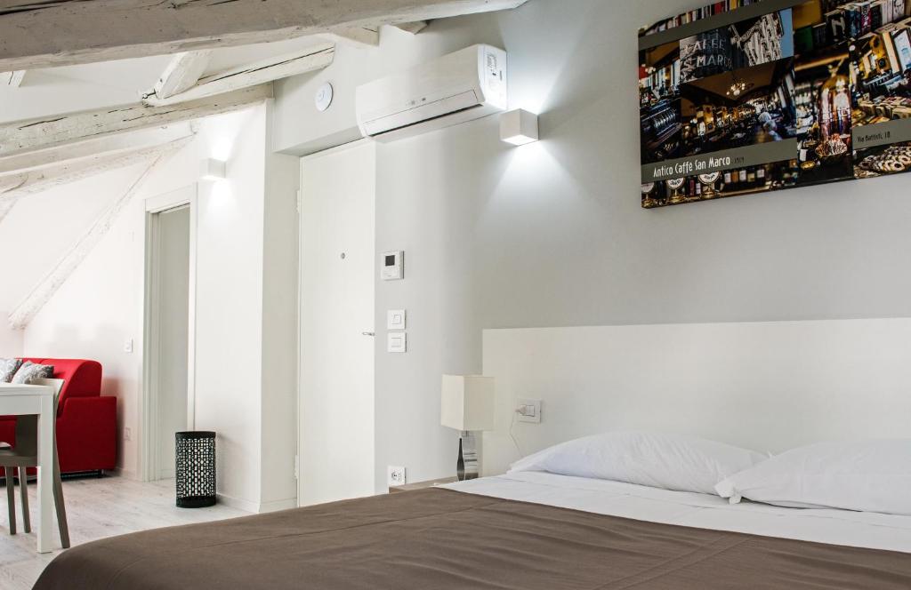 um quarto com uma cama e uma cadeira vermelha em DOMO Apartments - Trieste Goldoni em Trieste