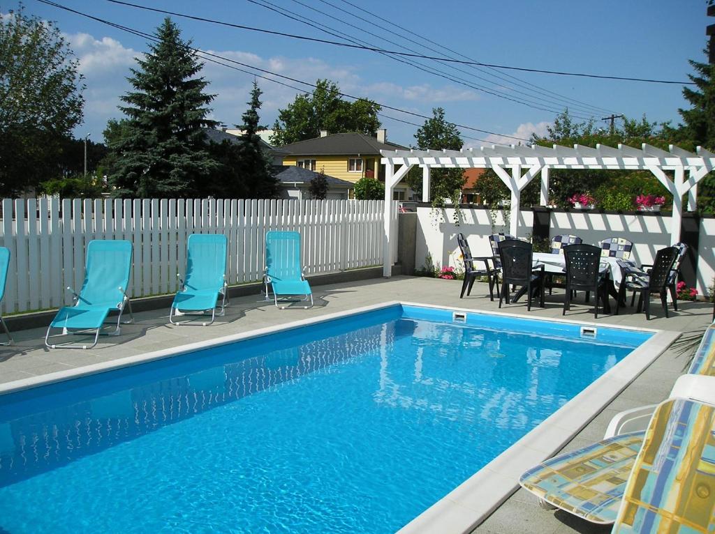 a swimming pool with chairs and a table and a white fence at Haus Sonnenhof in Siófok